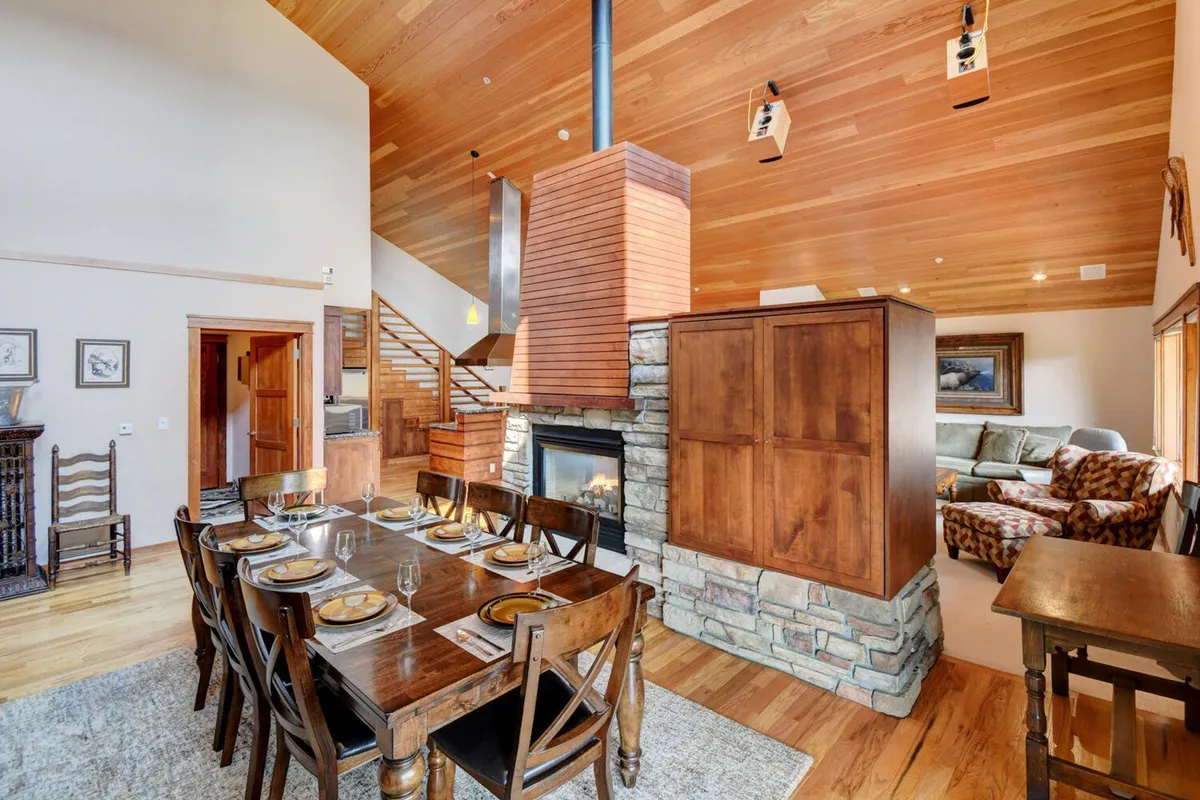 A beautifully set dining table is the focal point, surrounded by modern decor, a crackling fireplace, and seamless connection to a plush living area. The arrangement suggests intimate family dinners, celebrations, and a welcoming atmosphere for group gatherings.