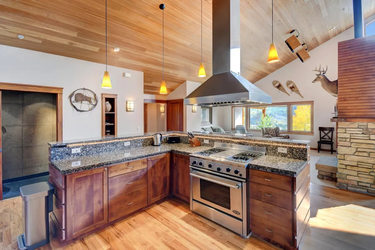 The chef's kitchen is highlighted here, featuring a large kitchen island with sleek granite countertops, stainless steel appliances, ample wooden cabinetry, and large windows. The space is both functional and stylish, ideal for preparing meals and hosting social occasions.