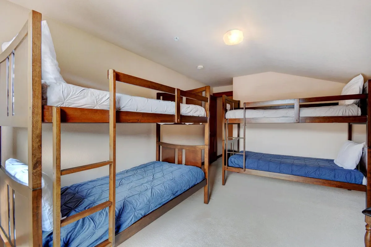 A playful bunk room with twin bunk beds, soft bedding, and plush carpeting. The space is cozy and thoughtfully arranged, perfect for children or groups to relax, read, or share stories before bedtime.