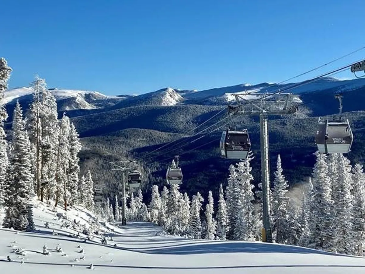 This image captures the exhilarating landscape of snow-covered slopes, ski lift gondolas, and distant mountains under a clear sky. The scene is alive with the excitement of winter sports like skiing and snowboarding, perfectly exemplifying the resort's proximity to Winter Park Resort and the variety of snow adventures available during the winter season.