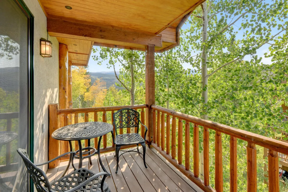 A serene deck area featuring a table and chairs, surrounded by trees and a wooden railing. The setup offers a tranquil spot for morning coffee, evening relaxation, or gathering to plan further adventures.